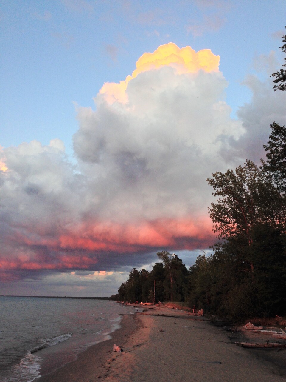 Photo of the sun reflected in a bank of clouds over a lake